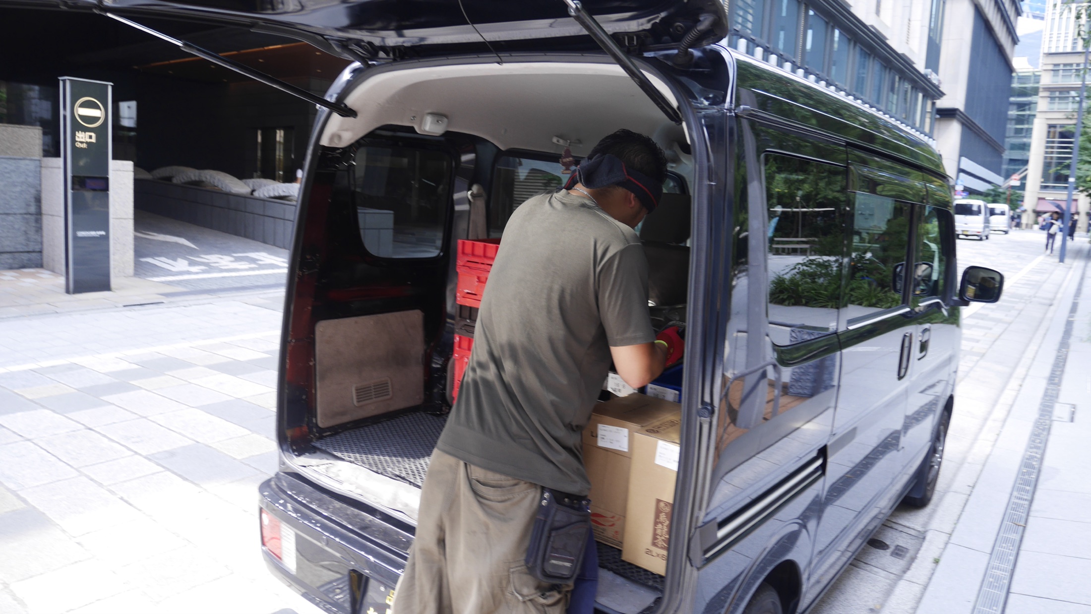 軽バンの荷室から荷物を運び出すところ