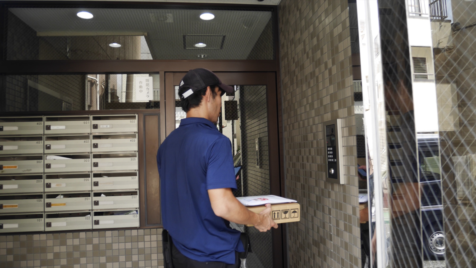 マンションのエントランスへ荷物を届けるところ